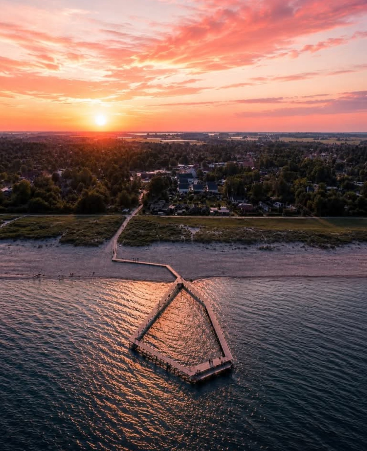 Kystlandskab og mole ved solnedgang fotograferet fra drone